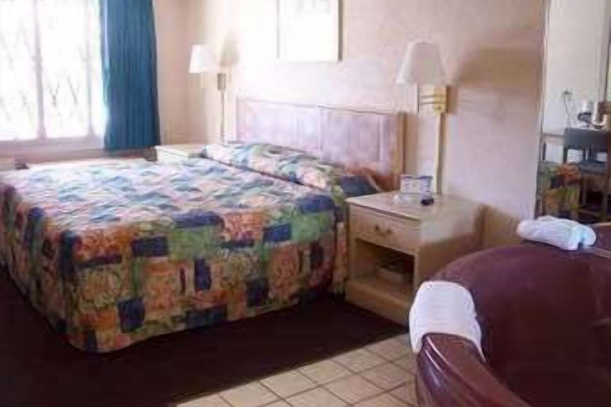 A hotel room with a bed, a desk, a chair, and a window with curtains.