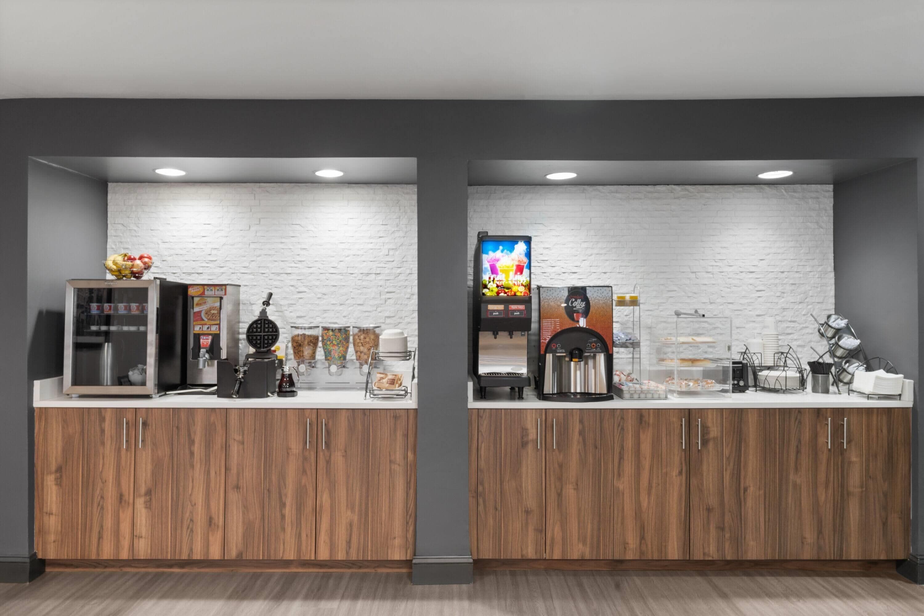 A modern breakfast bar with a white brick wall, wooden cabinets, and a coffee machine.