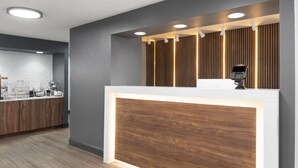 A modern reception desk with a wooden panel, a digital kiosk, and a counter with a white surface. - Super 8 by Wyndham Chattanooga East/Hamilton Place (Chattanooga)