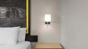 Un dormitorio con cama, una mesita de noche, una lámpara de pared y un cuadro con una cascada.