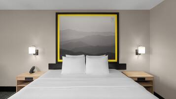 A hotel room with a large bed, two bedside tables, a phone, and a wall-mounted artwork.