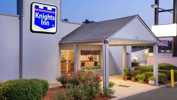 A Knights Inn with a covered entrance, a visible restaurant, and potted plants. - Knights Inn Augusta at Boy Scout Rd (Augusta)