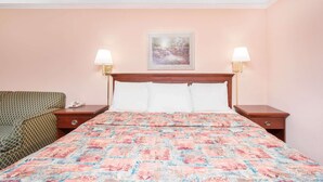 A hotel room with a bed, two bedside tables, a green patterned sofa, and a painting on the wall. - Knights Inn Augusta at Boy Scout Rd (Augusta)