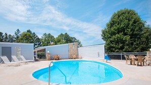 A swimming pool with lounge chairs and a stone wall. - Knights Inn Augusta at Boy Scout Rd (Augusta)