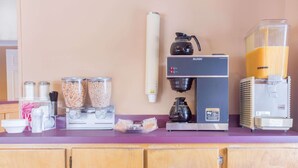 A kitchen counter with a coffee machine, a blender, and containers of coffee beans and sugar. - Knights Inn Augusta at Boy Scout Rd (Augusta)