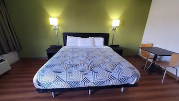 A hotel room with a bed, two bedside tables, a desk, and two chairs.