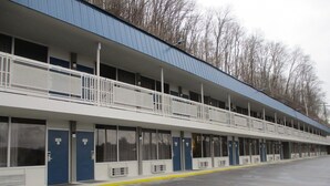 A motel with a two-story structure, featuring a row of rooms with individual air conditioning units and a covered outdoor area. - Motel 6 Chilhowie, VA  I-81 (Chilhowie)