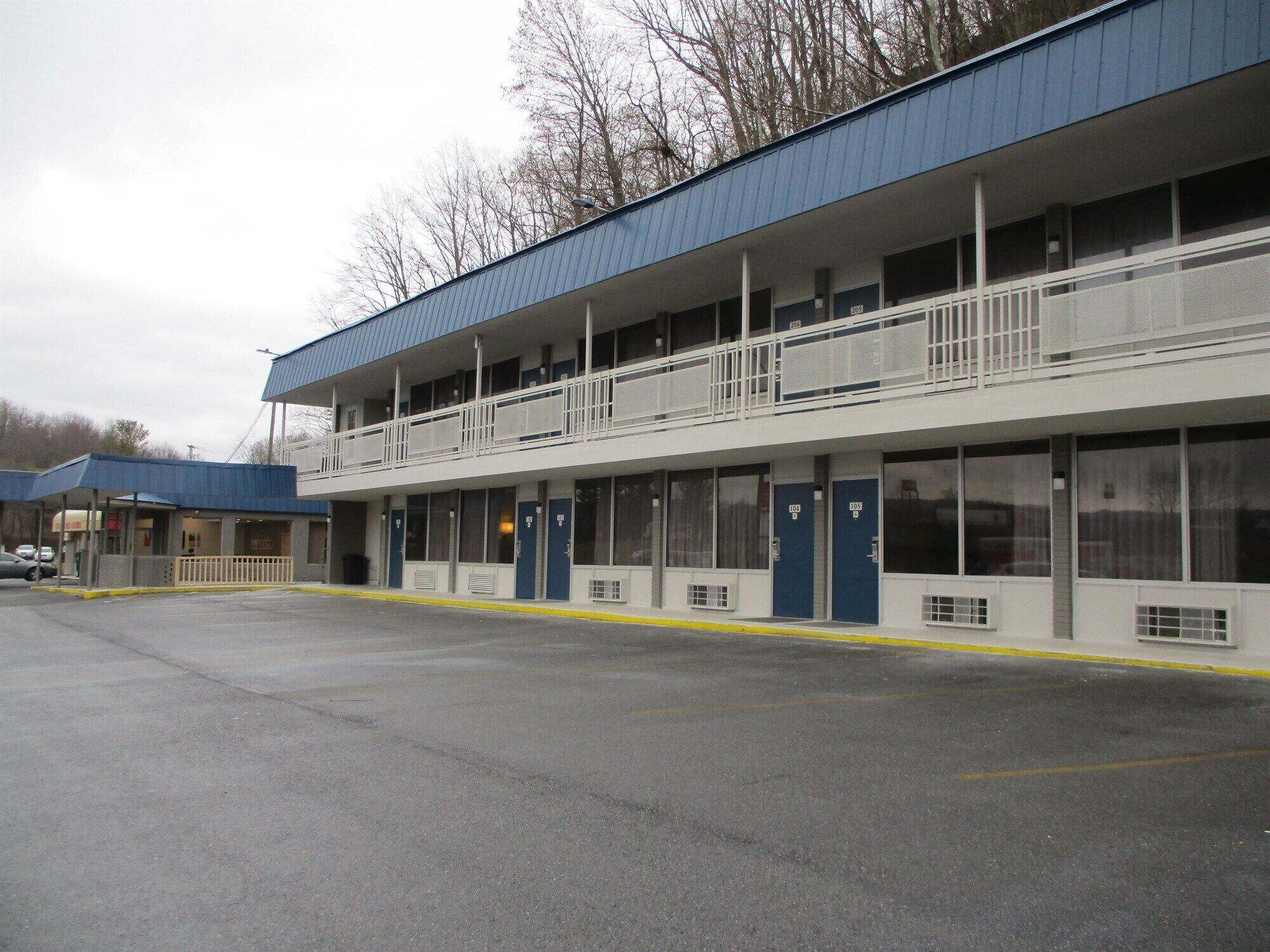 A motel with a two-story structure, multiple rooms, and a covered parking area.