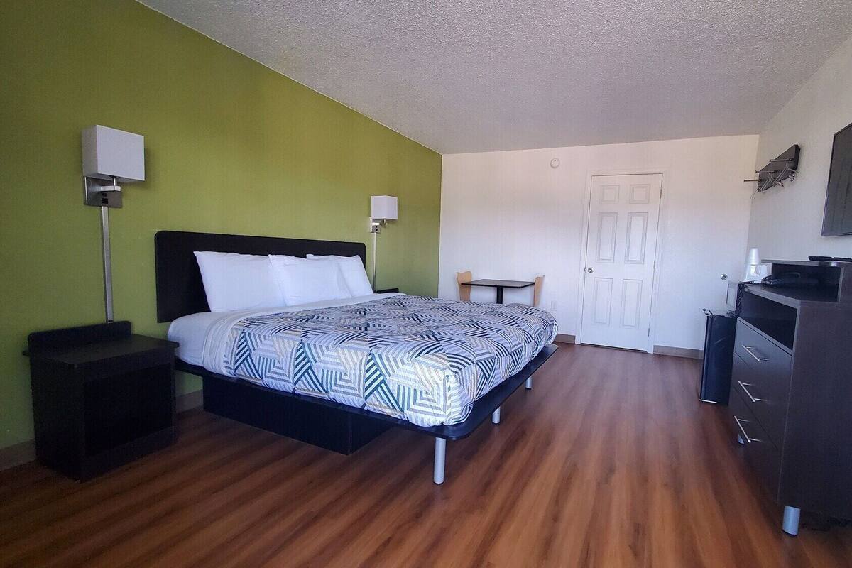 Une chambre à coucher comprenant un lit, un bureau, une chaise, une télévision et une armoire.