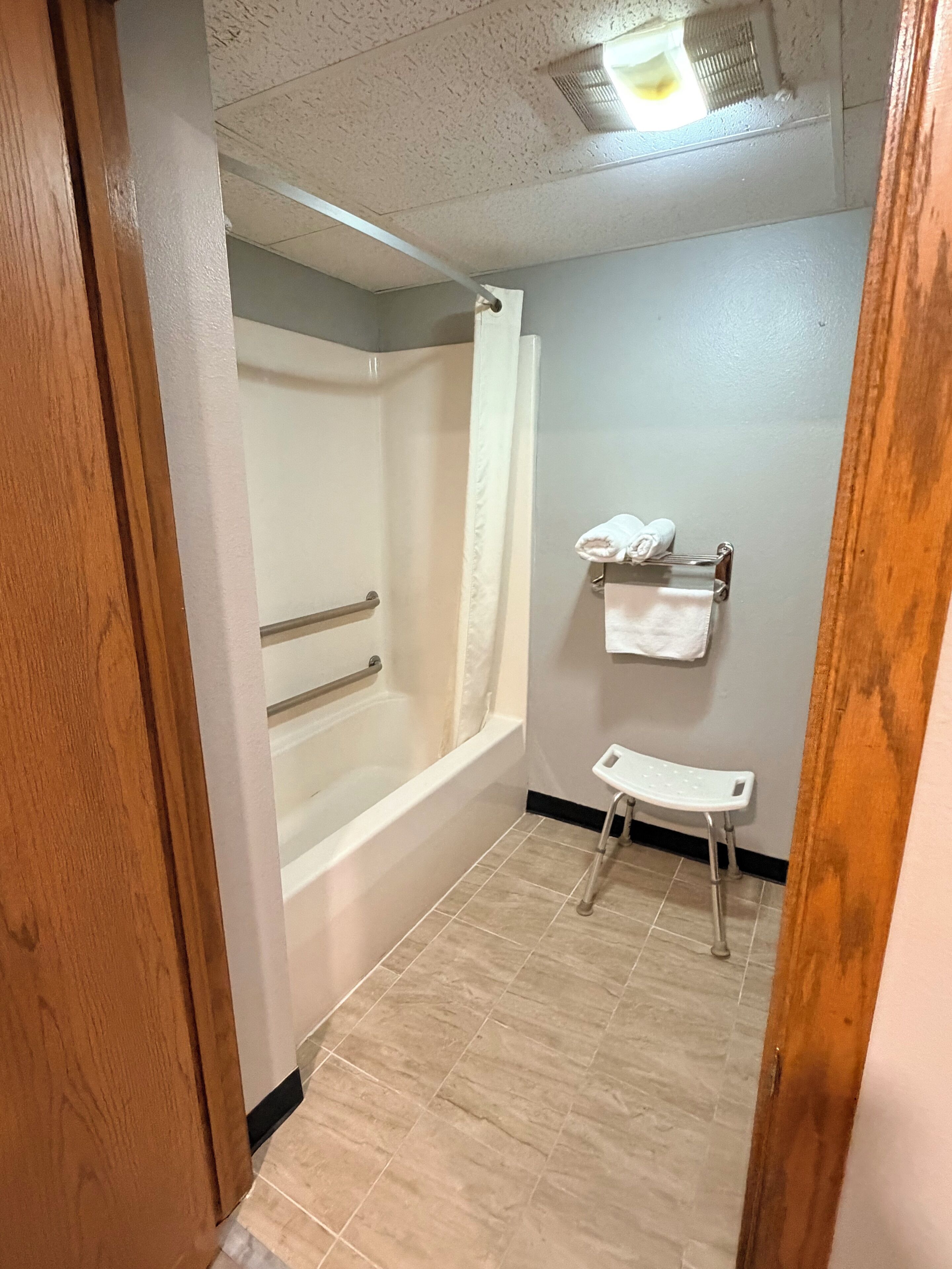 A bathroom with a bathtub, shower, and a bench.