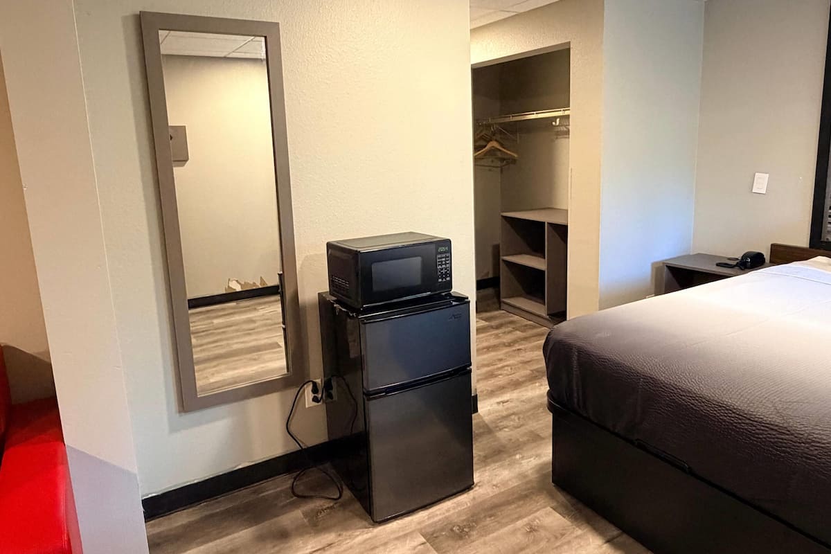 Quarto de hotel com cama, frigorífico, micro-ondas, roupeiro e secretária.