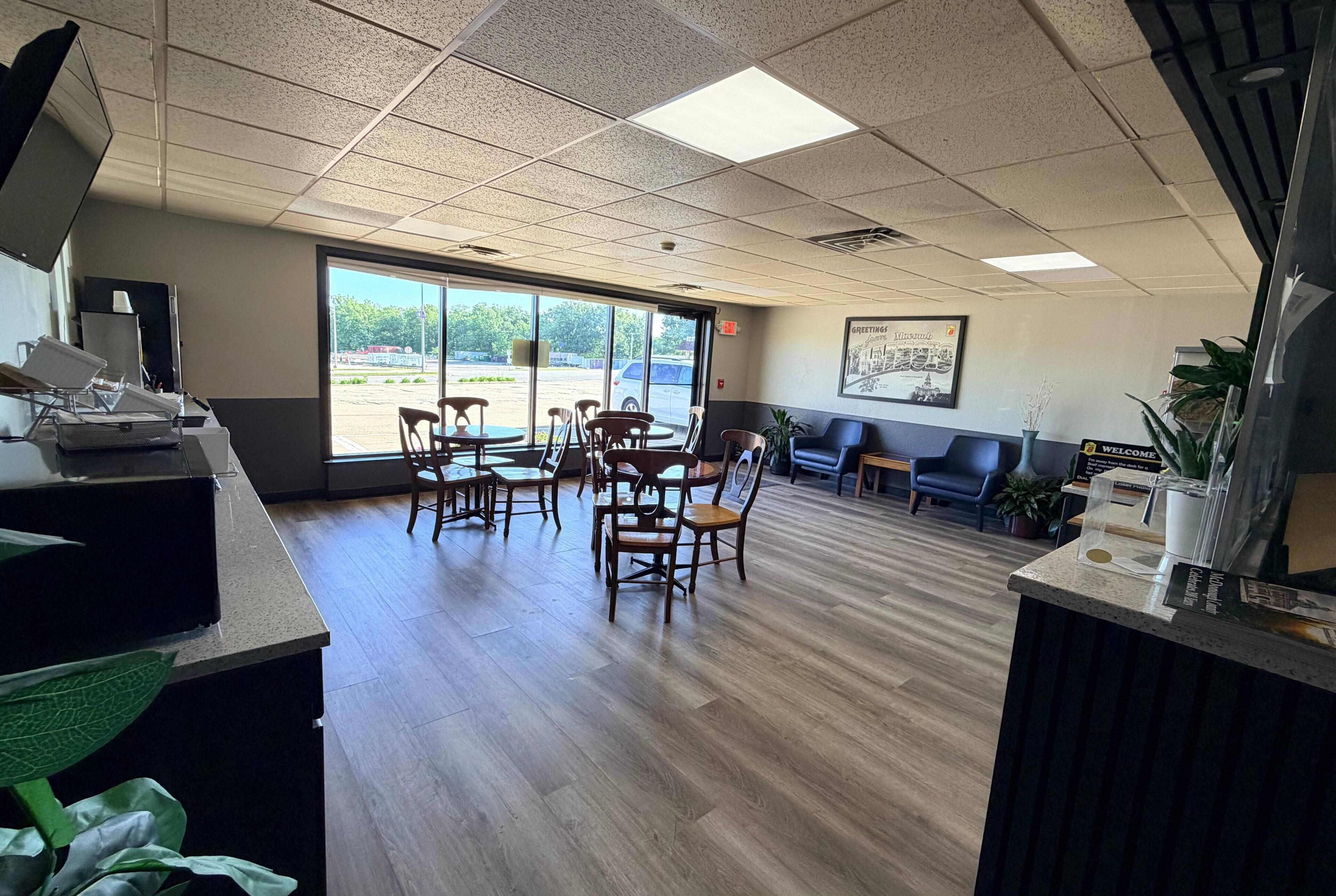 A reception area with a counter, chairs, a bench, and a large window.