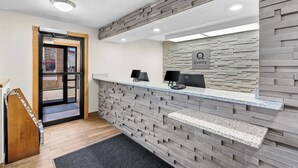 A reception area with a modern design, featuring a stone wall, a reception desk with computers, and a sign that reads "Quality." - Quality Inn Beaver I-15 (Beaver)