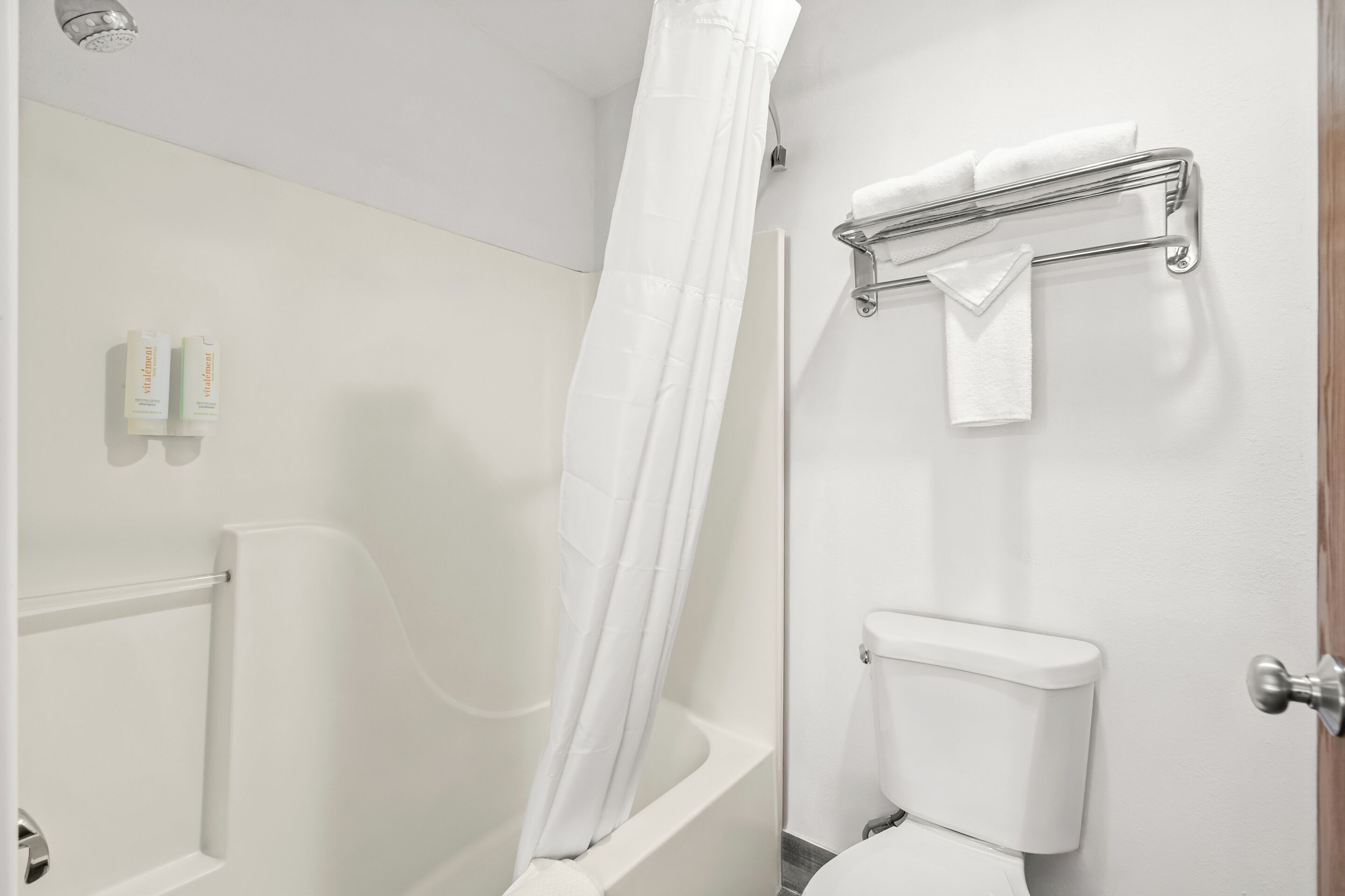 A bathroom with a shower, toilet, and towel rack.
