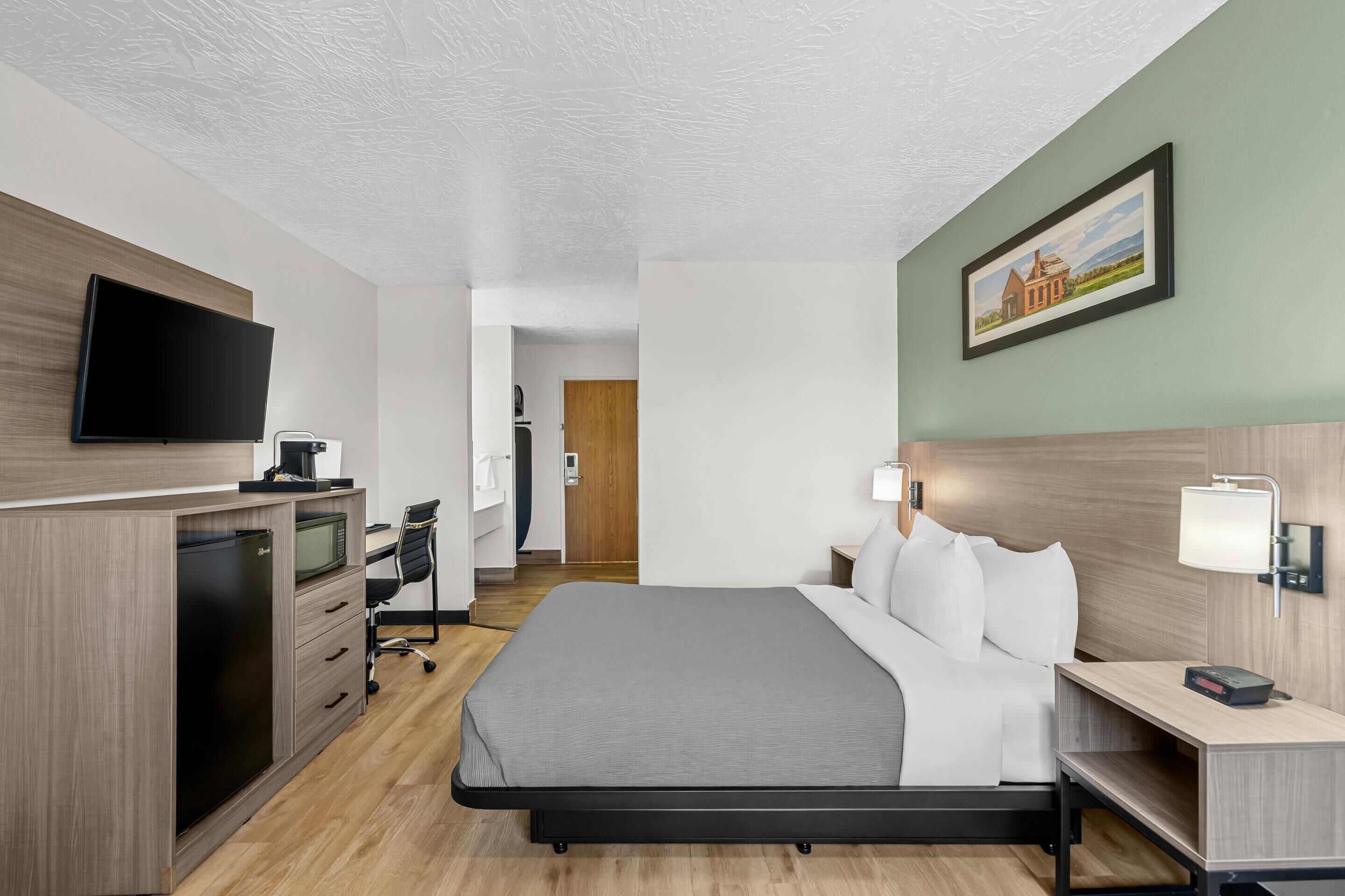 Una habitación de hotel moderna con cama, escritorio y televisión.