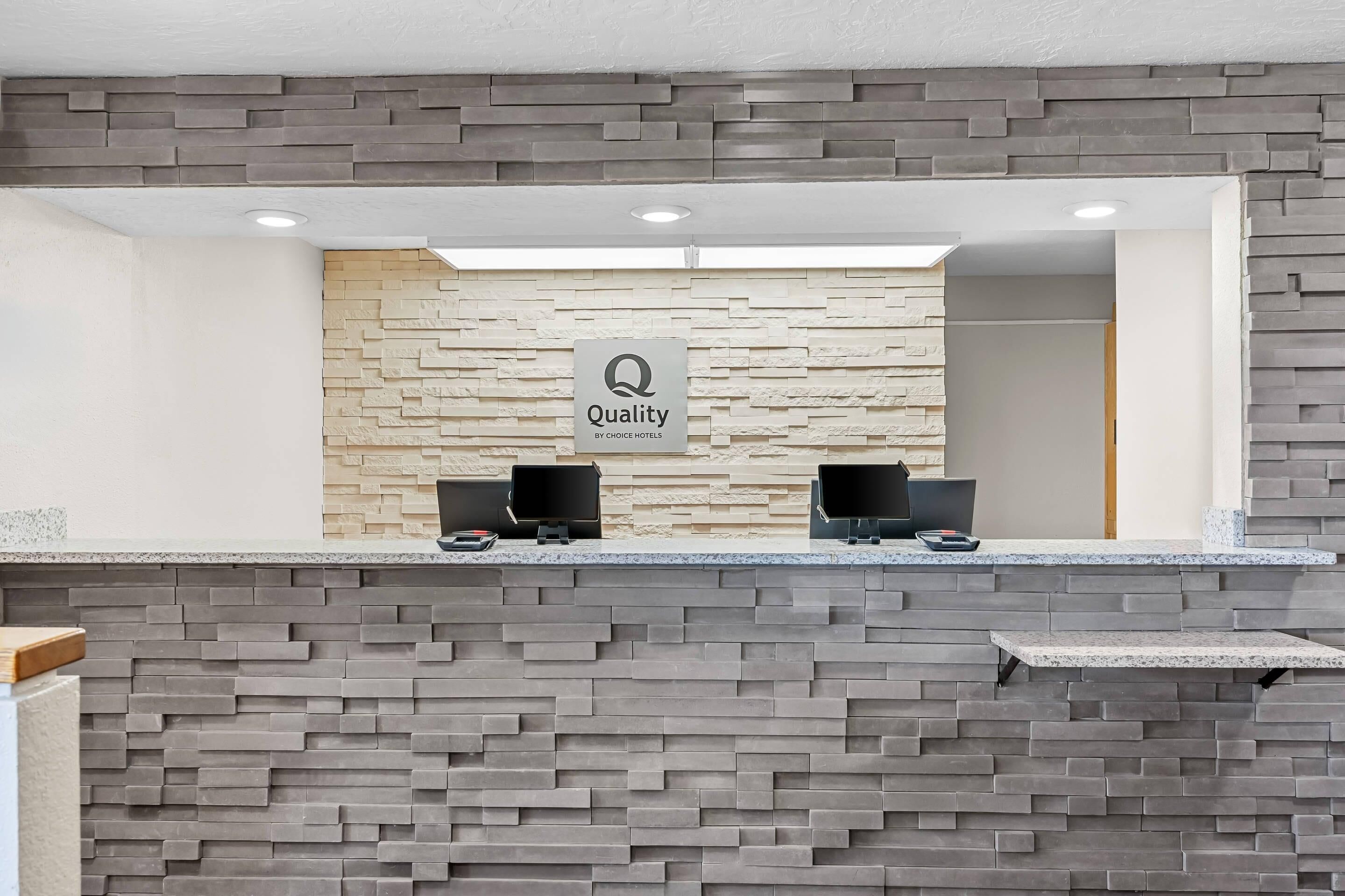 A reception area with a stone wall and two computer monitors.