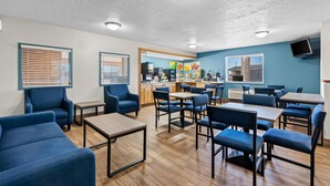 A modern restaurant with blue seating, wooden flooring, and a kitchen area visible through the entrance. - Quality Inn Beaver I-15 (Beaver)