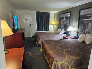 A hotel room with two beds, a desk with a computer, a lamp, and a large framed picture on the wall. - Budgetel Inn & Suites (Moody)