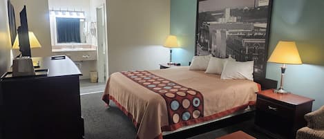 Habitació d'hotel amb un llit, dues làmpades de nit, un escriptori, una cadira i un gran quadre de paisatge urbà a la paret.