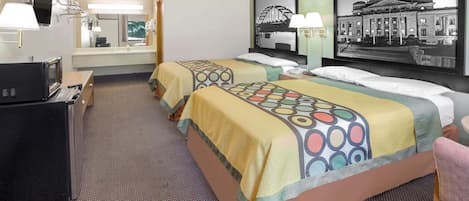 A hotel room with two beds, a desk with a TV, and a large framed picture of a building.