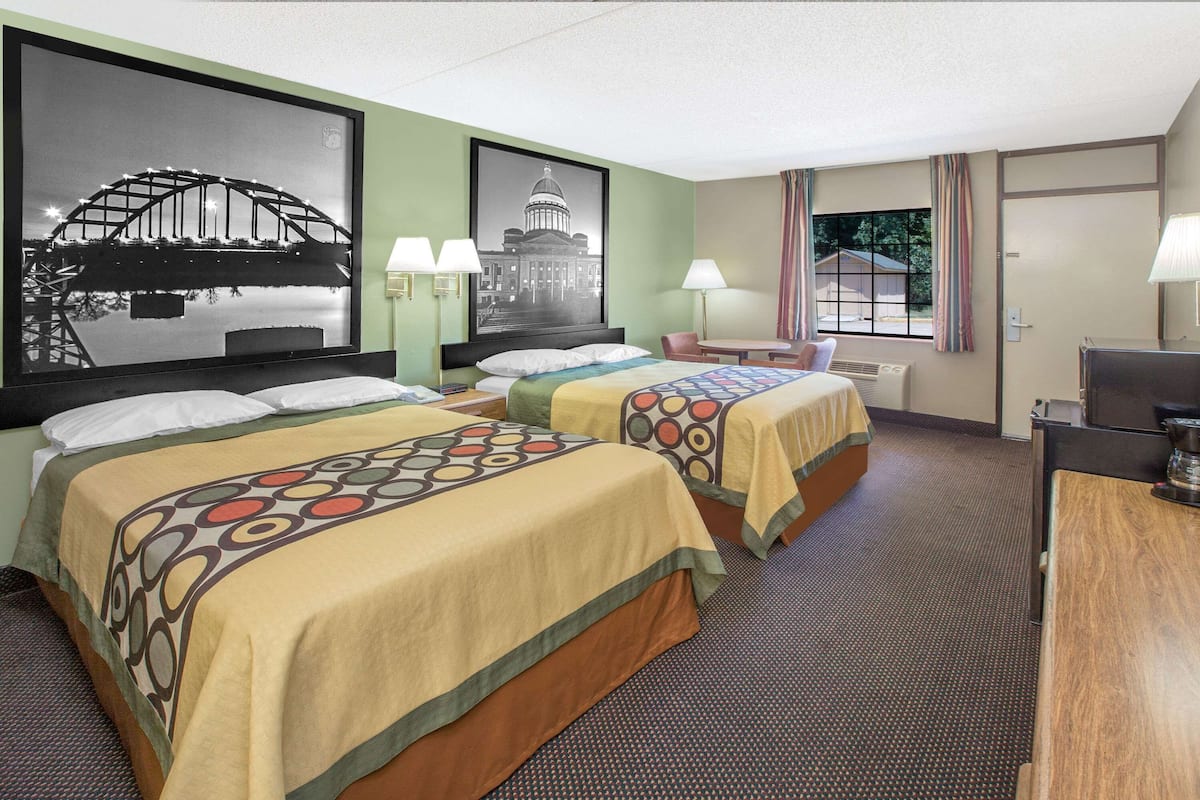 Une chambre d’hôtel avec deux lits, un bureau, une chaise et deux lampes.