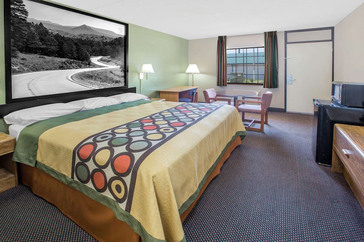 Une chambre d’hôtel équipée d’un lit, d’un bureau, d’une chaise, d’une télévision et d’une grande fenêtre.