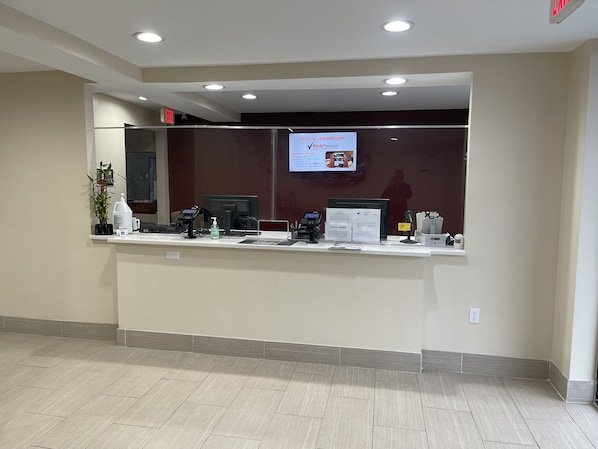 A reception desk with a computer, phone, and informational sign.
