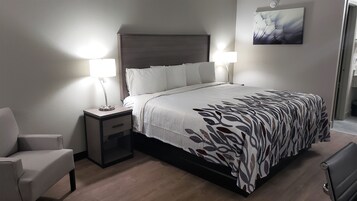 Habitación de hotel ordenada con cama, mesitas de noche, una silla y un cuadro en la pared.