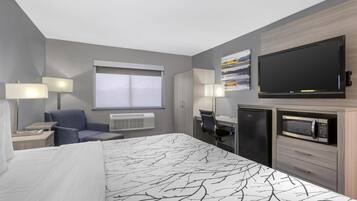 A hotel room with a bed, a desk, a chair, a TV, a microwave, and a window.