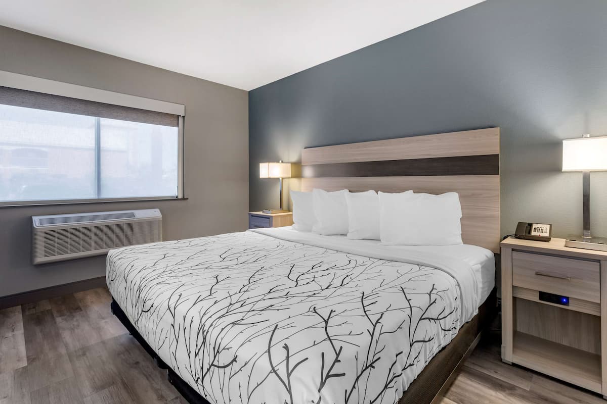 Relax in a stylish room with a large bed, wooden headboard, and a window offering a view of the outside.