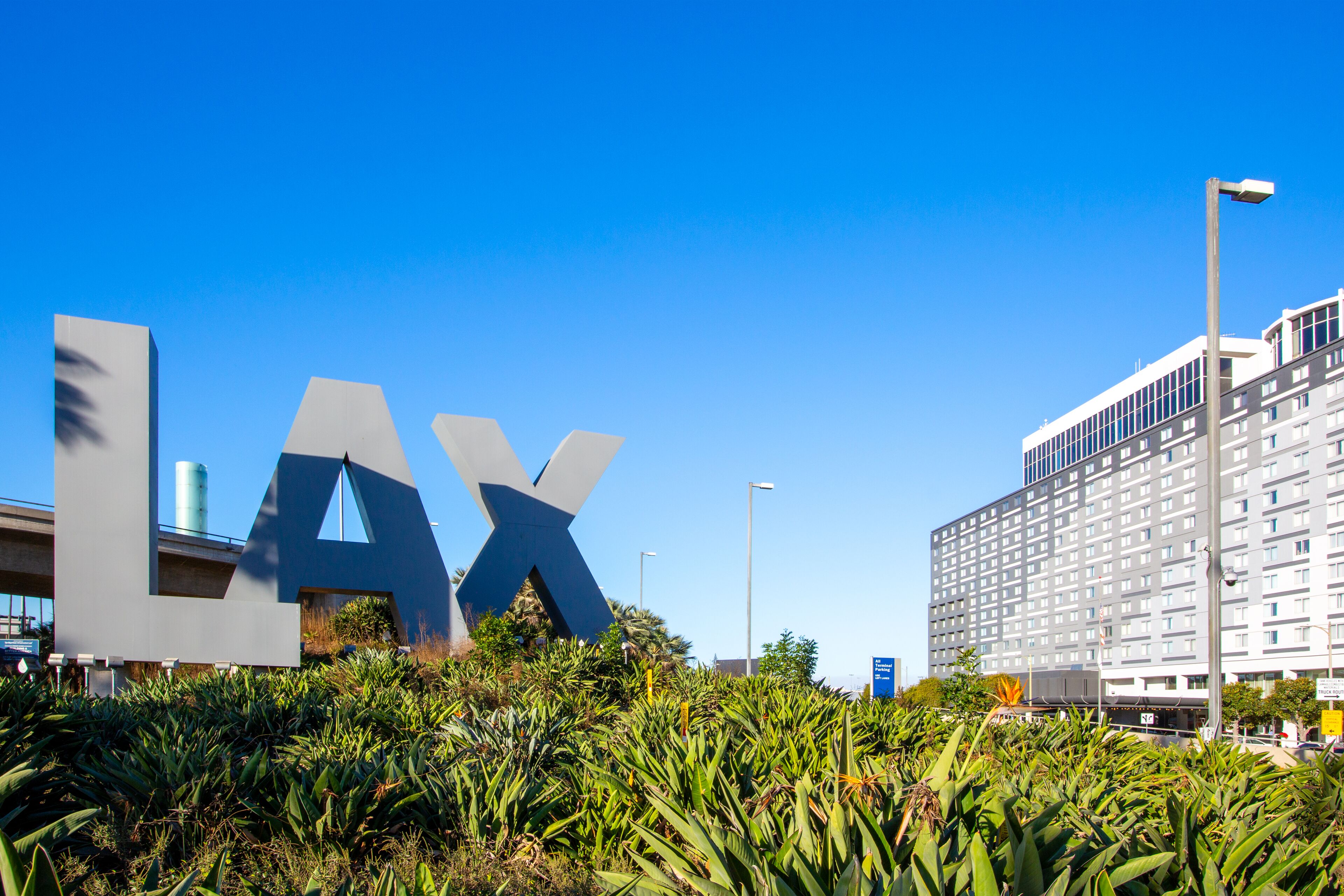 A building with a large 'LAX' sign in the foreground, surrounded by greenery.
