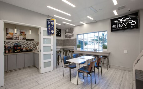 A modern hotel kitchen with a dining area, a snack bar, and a large window providing a view of the outdoors.