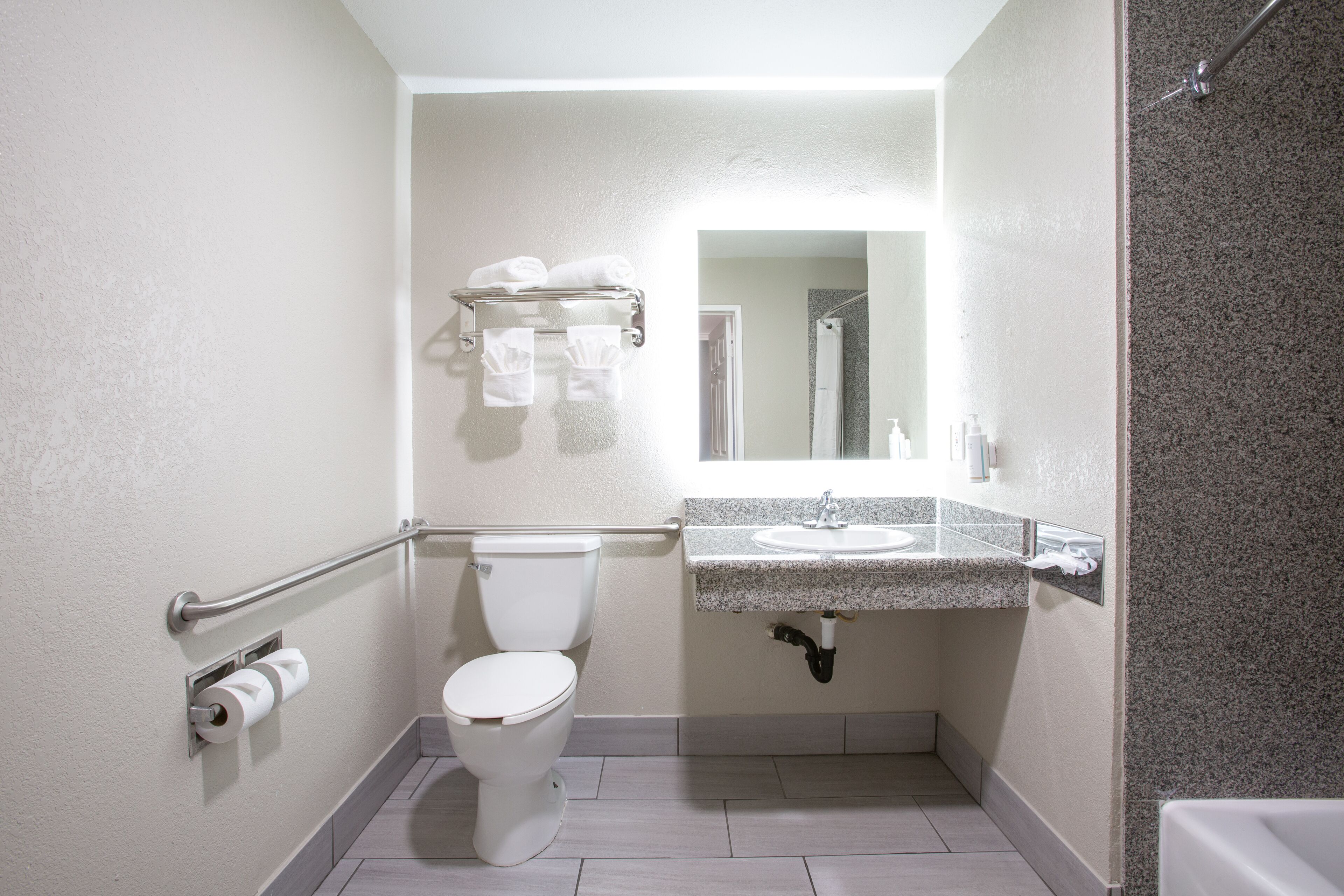Un baño con inodoro, lavabo, espejo y toallero.