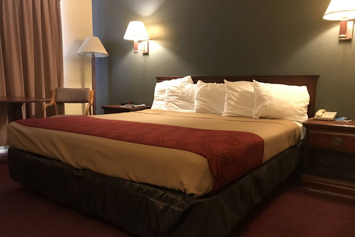 Ett hotellrum med en stor säng, två sänglampor, ett nattduksbord och en stol.