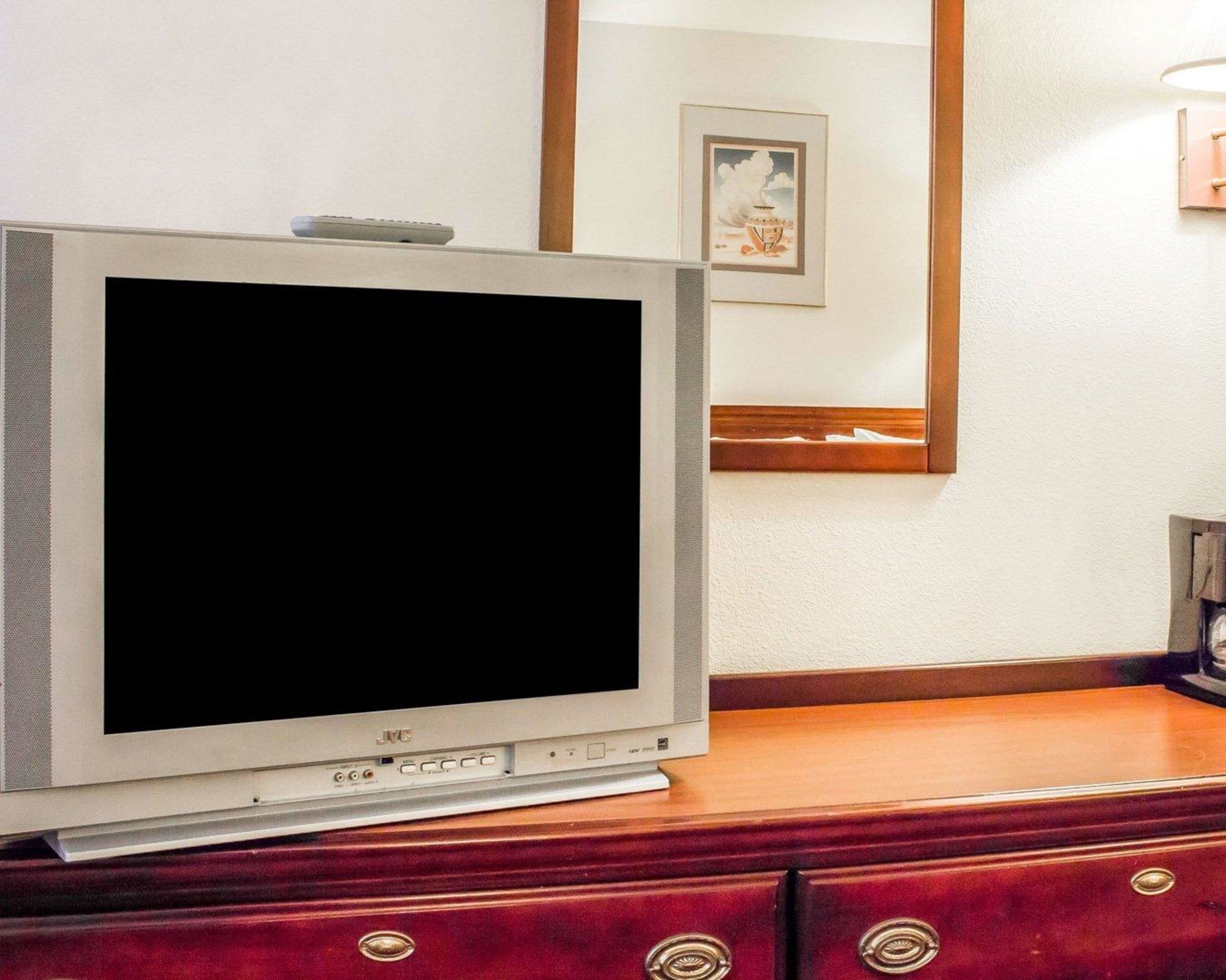 A JVC CRT television on a wooden dresser in a hotel room.