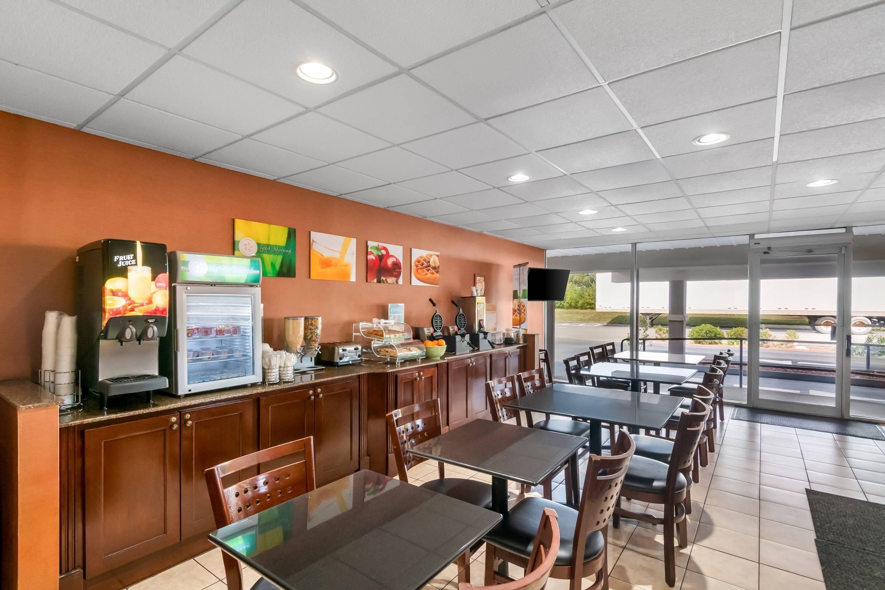 A restaurant with a counter, seating area, and large windows.