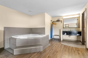 A modern bathroom with a large freestanding bathtub, a vanity with a mirror, and a shower area.