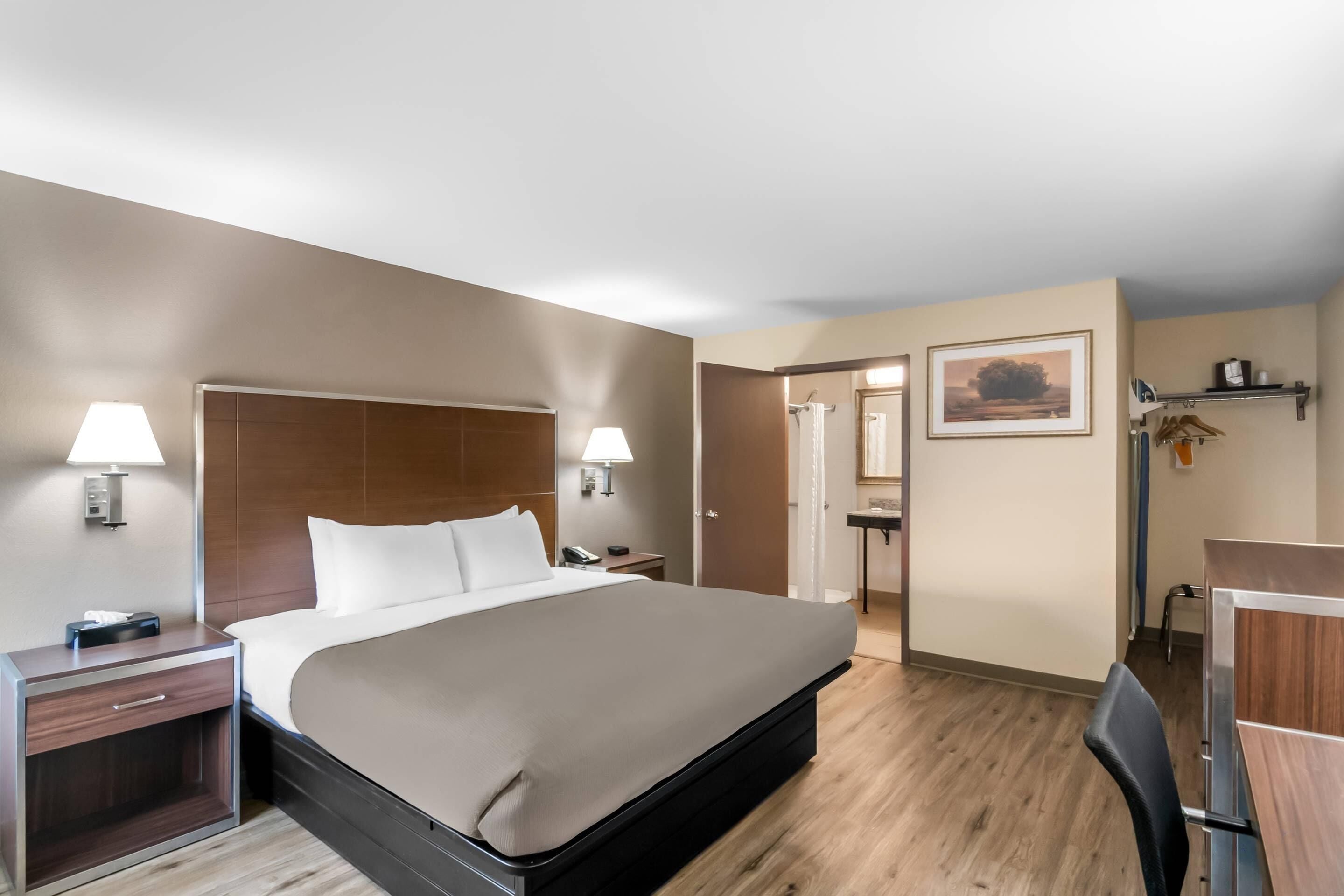 Una habitación de hotel con una cama grande, mesitas de noche con lámparas, un escritorio y una silla.