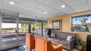 A lobby with a sofa, a reception desk, and a view of the outside.