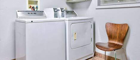 A laundry area with a washing machine and dryer, a chair, and an air conditioning unit.