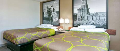 A hotel room with two single beds, a nightstand, a lamp, and two framed pictures on the wall.