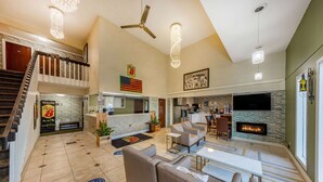 A spacious living area with a fireplace, comfortable seating, a kitchen, and a staircase leading to an upper level. - Super 8 by Wyndham El Dorado (El Dorado)