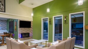 A modern lounge area with a stone fireplace, comfortable seating, and large windows. - Super 8 by Wyndham El Dorado (El Dorado)