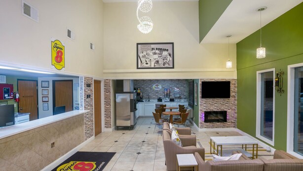 A hotel lobby with a reception desk, seating area, and a kitchen in the background. - Super 8 by Wyndham El Dorado (El Dorado)