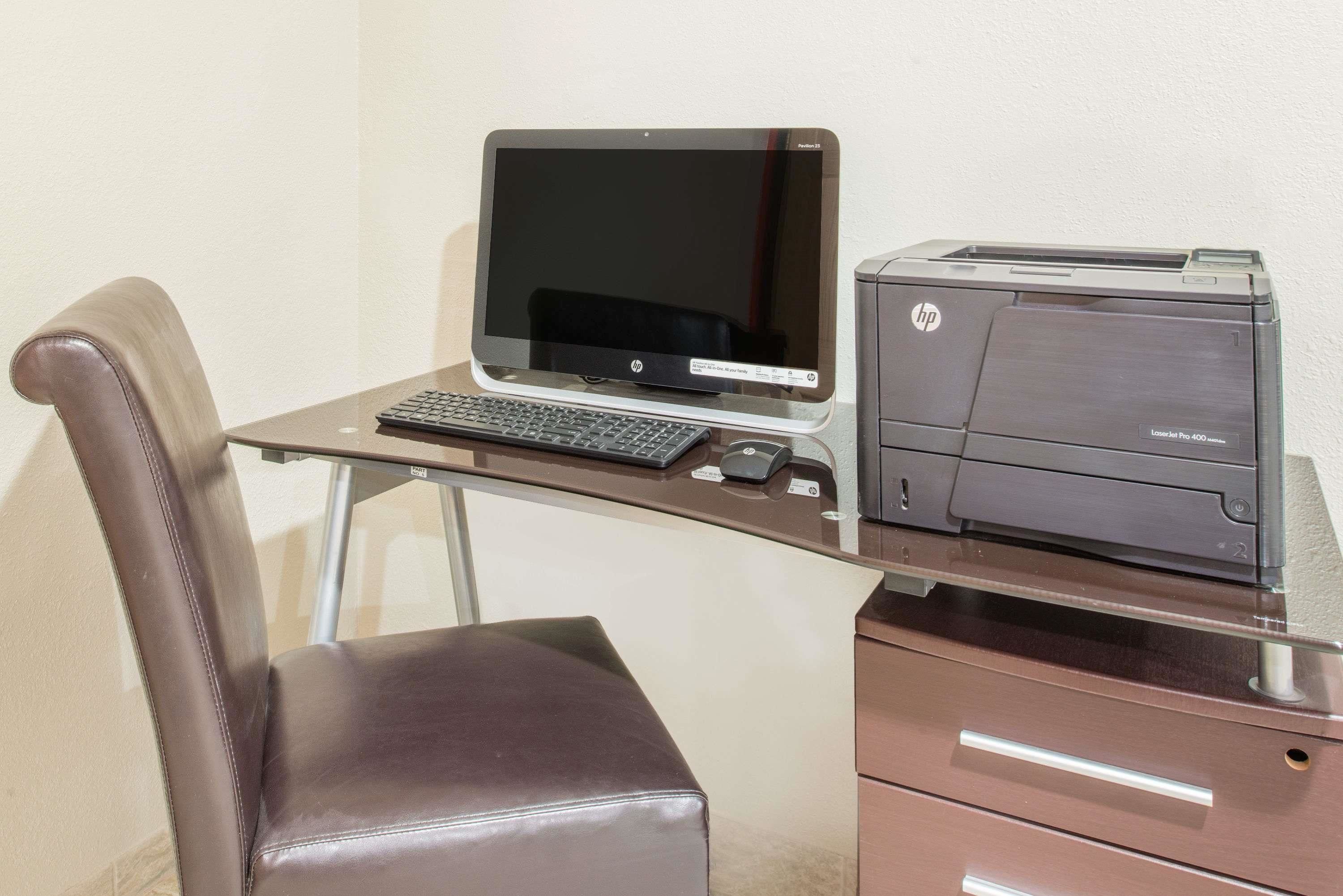 Een bureau met een laptop, toetsenbord en een HP-printer.