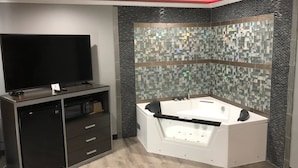 Une salle de bain moderne dotée d’une grande baignoire, d’un téléviseur à écran plat et d’un four à micro-ondes encastré.