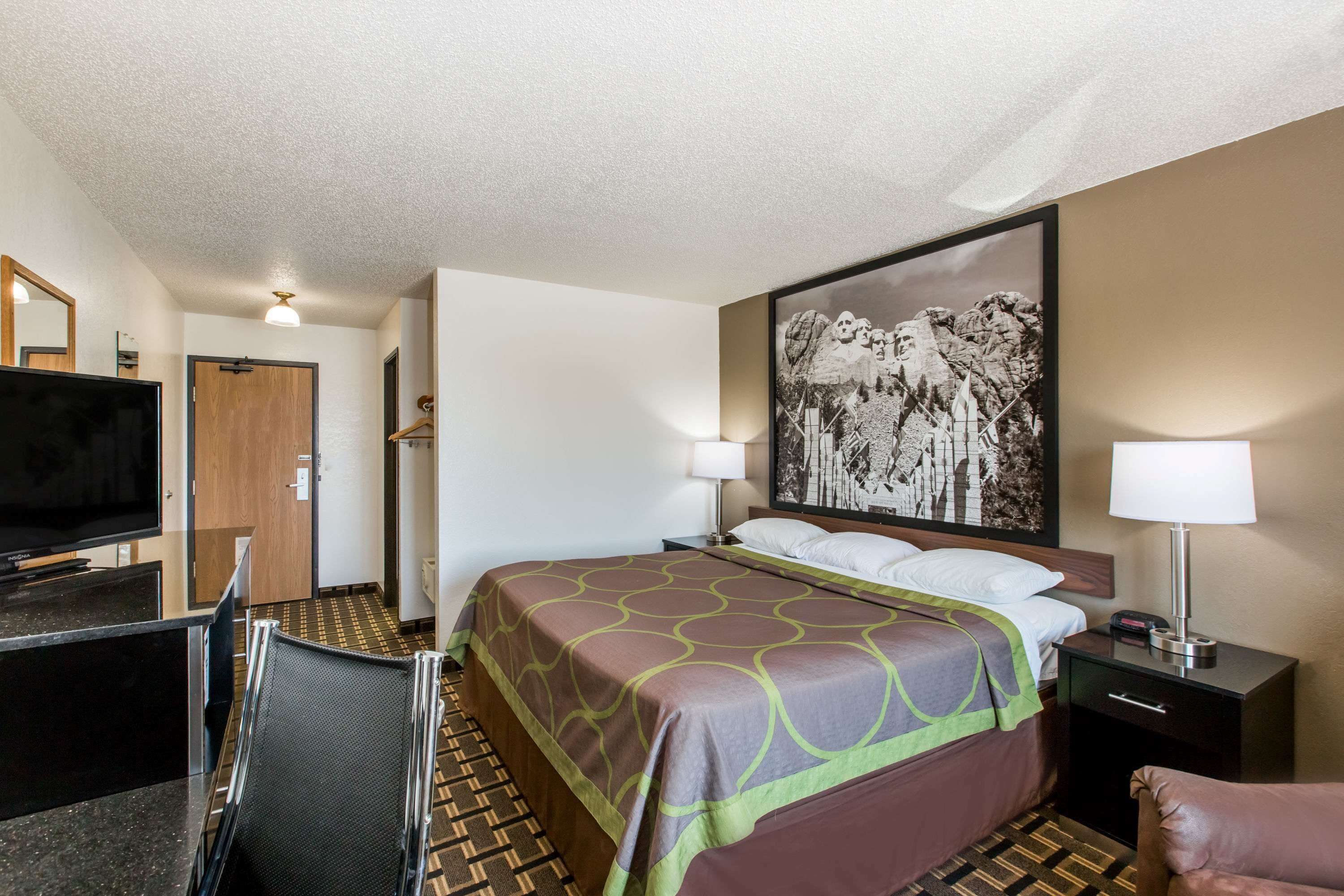 A hotel room with a bed, a TV, a desk, and a chair.