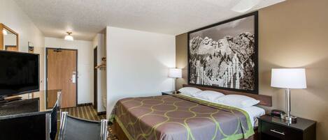 A hotel room with a bed, a TV, a desk, and a chair.