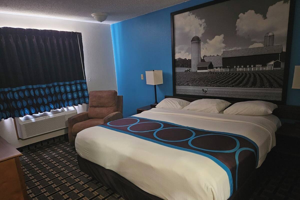 Een hotelkamer met een groot bed, een stoel, een bureau en een raam met gordijnen.