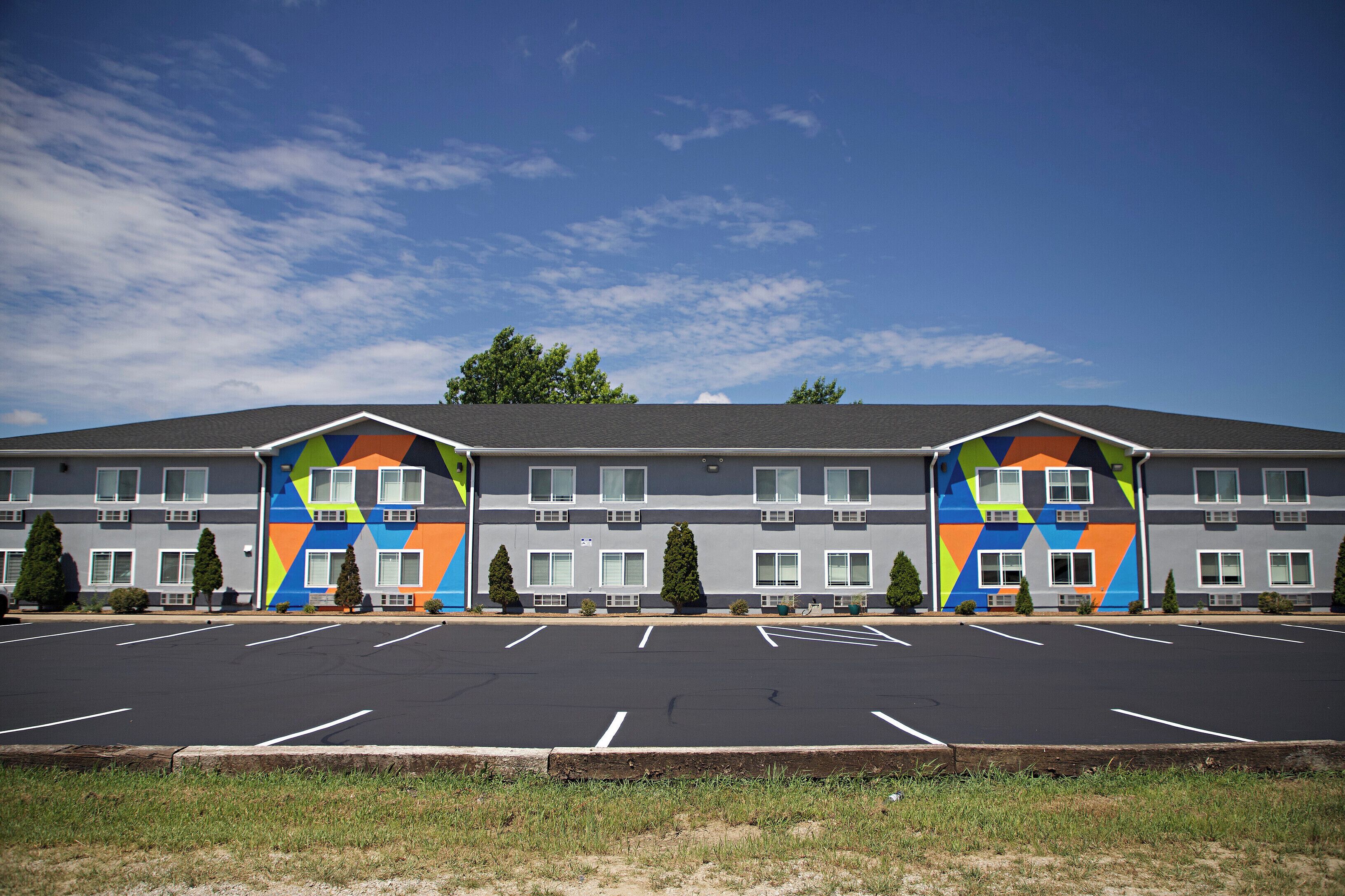 A hotel with a parking lot and a colorful facade.